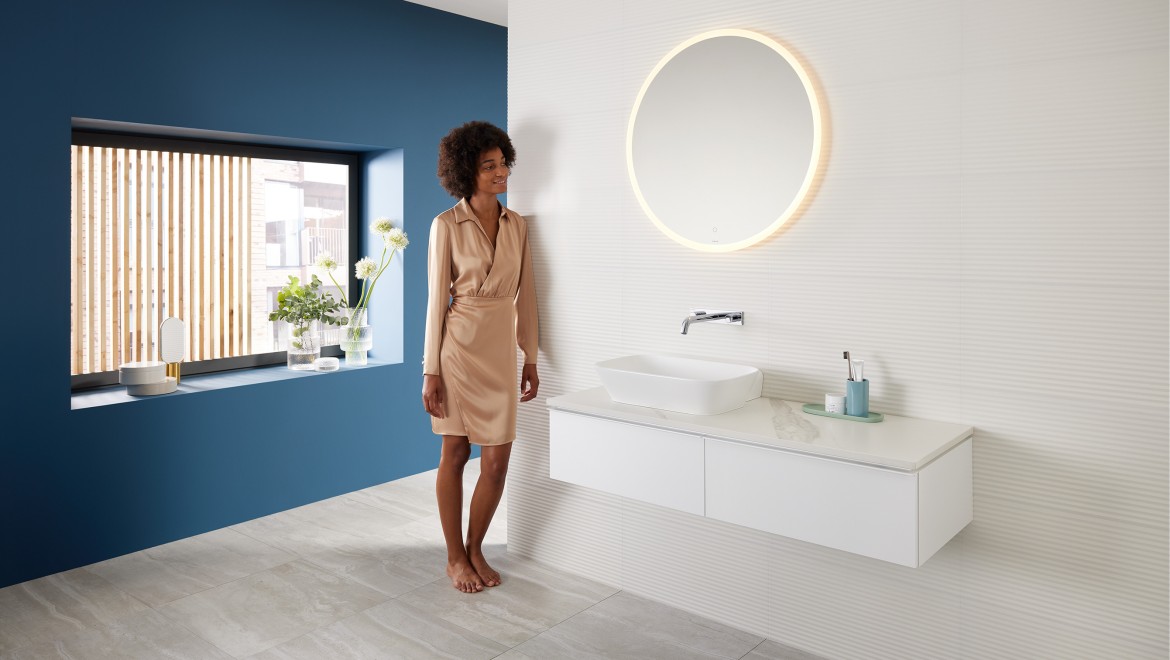 Donna in piedi in un bagno creato con la linea Mix & Match di Geberit. Donna in piedi in un bagno creato con la linea Mix & Match di Geberit.