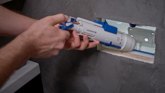 Un installatore monta una valvola di scarico Geberit all’interno di una cassetta di risciacquo da incasso. (© Ben Huggler)